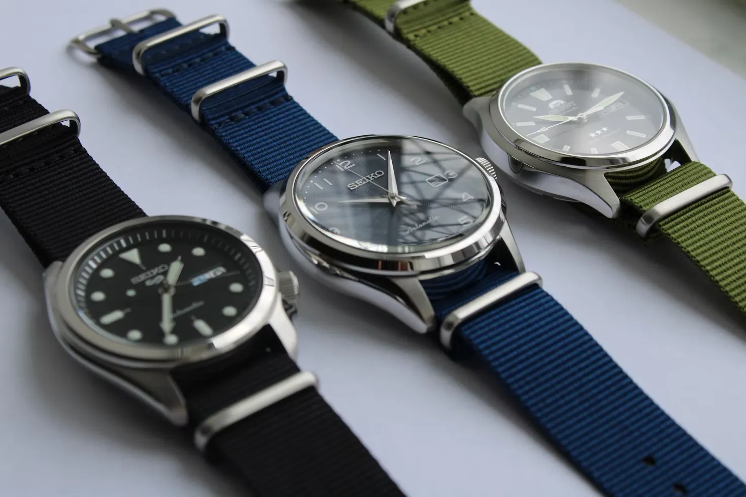 Trois montres automatiques sur bracelets NATO noir, bleu et vert